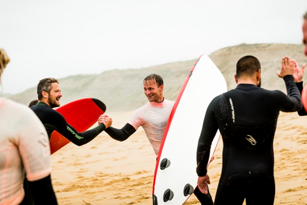 Men high fiving holding surf boards on the beach