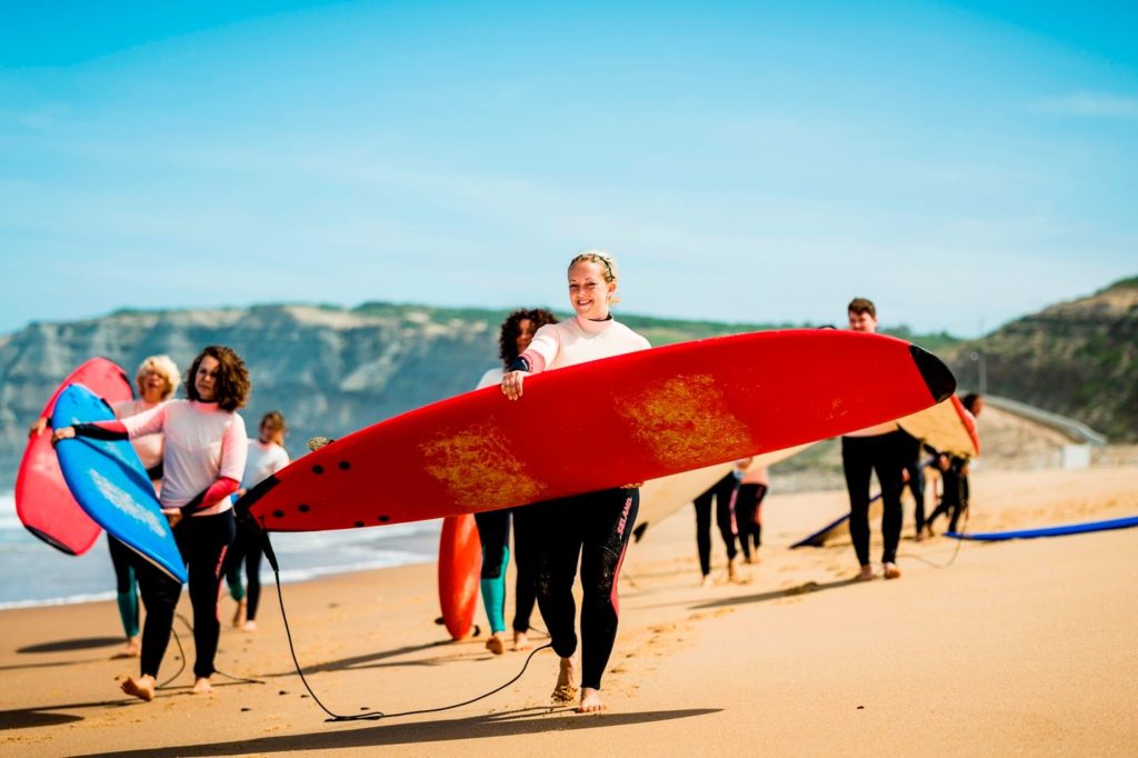 Surfers carrying their boards along a sunny beach into the water