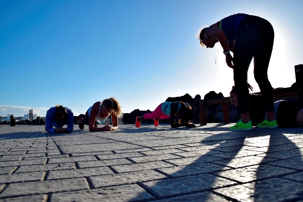 Fitness guests and instructor planking in the street in the sun