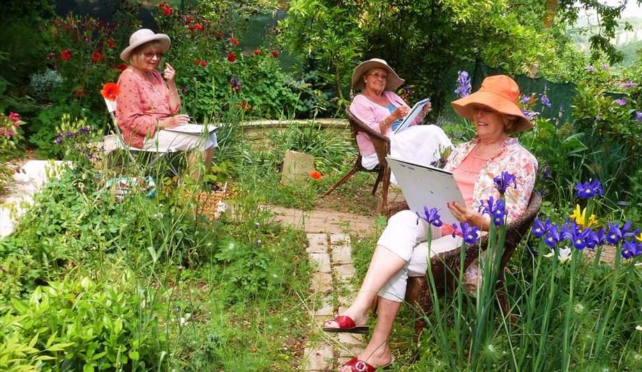 three women painting in a garden