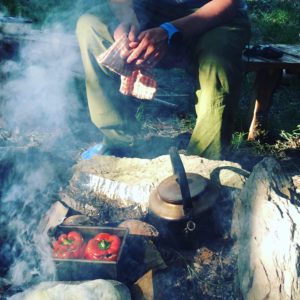 man cooking peppers on camp fire