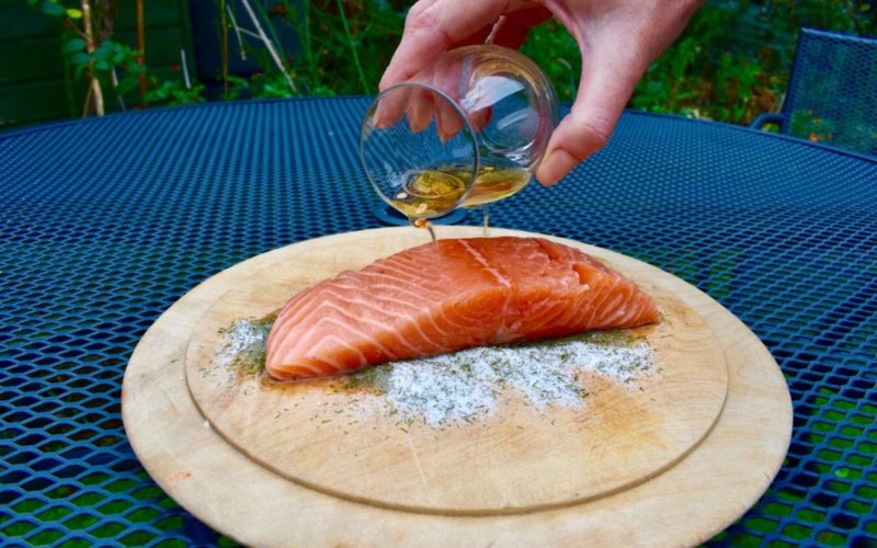 glass pouring oil over salmon fillet