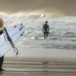 female surfer carries surf board into sea