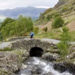 two cyclists over stone bridge