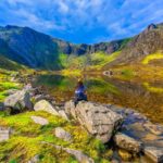 female hiker sitting down to admire mountain view