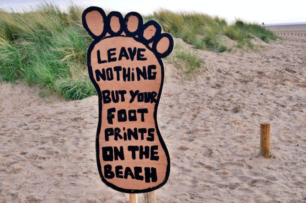 sign on a beach promoting responsible travel