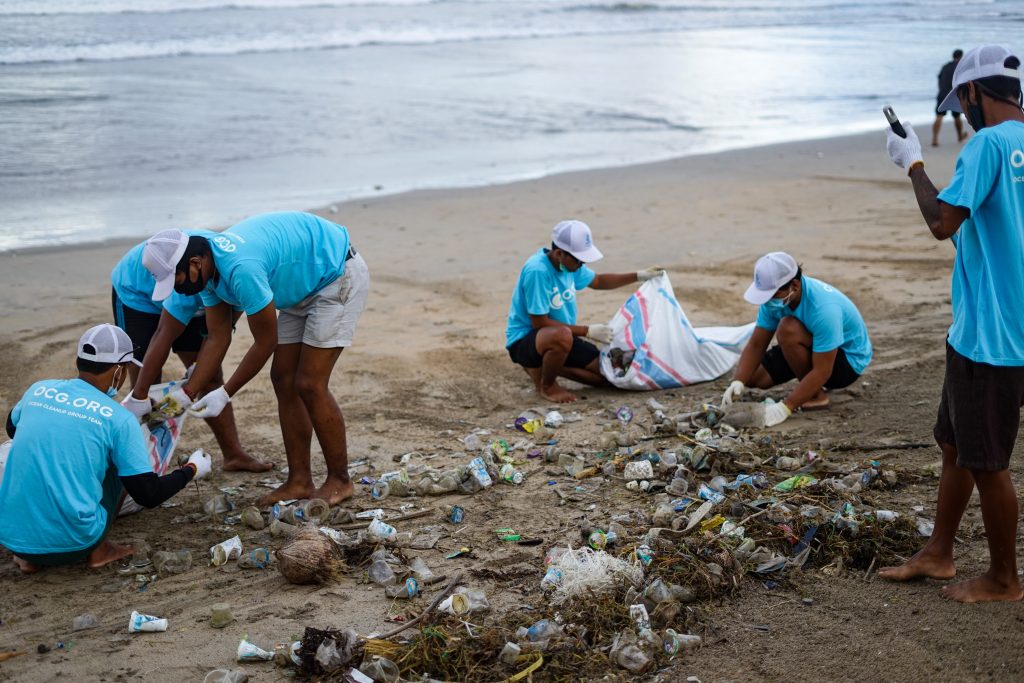 people cleaning plastic off a beach